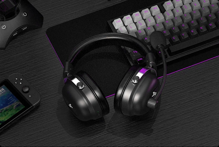 Auscultadores Commander pousados numa secretária, entre um teclado e uma consola portátil